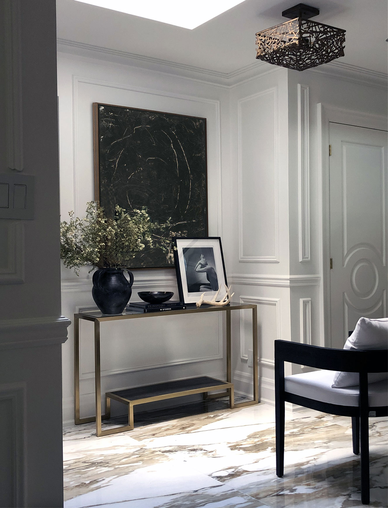Black statement wall art hanging in a foyer over a console table